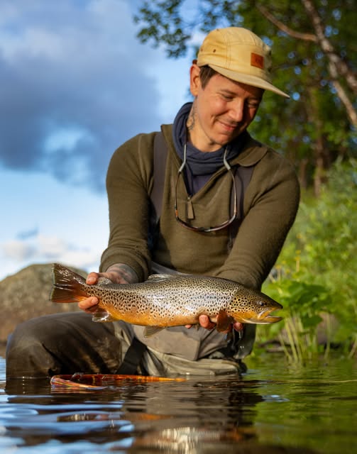 Fiskare med öring i kvällsljus.