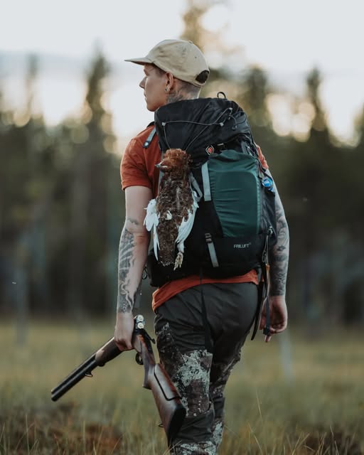 Jägare med ryggsäck på väg genom skogen.